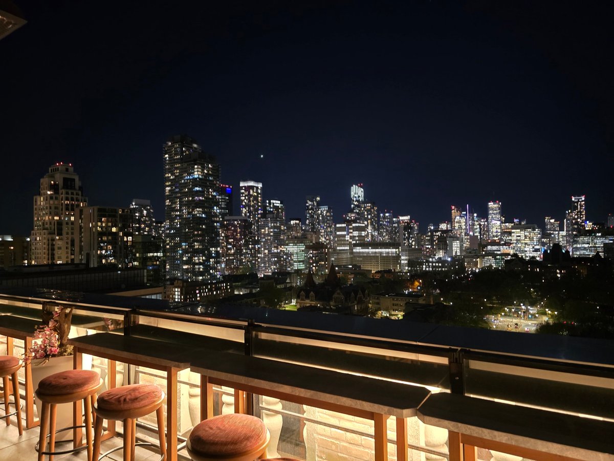 Beautiful city skyline at night seen from a rooftop bar with cozy seating and glowing lights