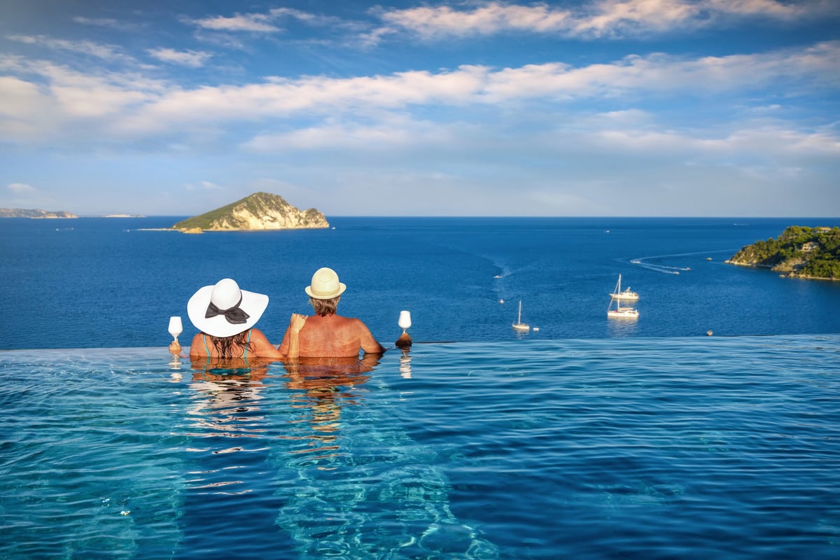Couple in a swimming pool watching the summer sunset over the Mediterranean sea