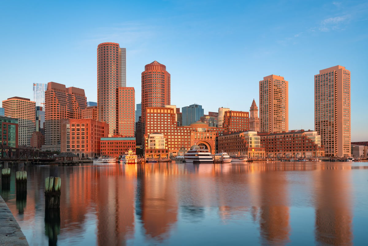 Modern cityscape at dawn with waterfront buildings reflected in calm water