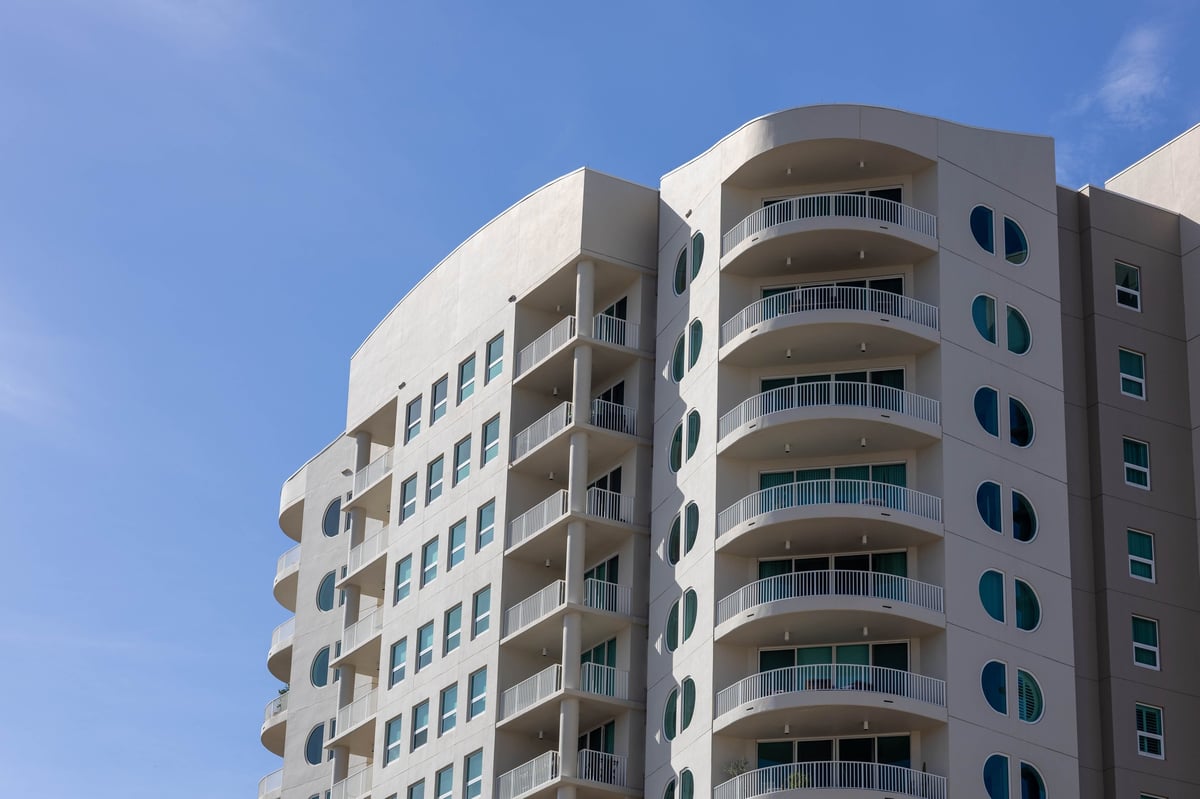 A contemporary residential building with curved balconies against a clear blue sky