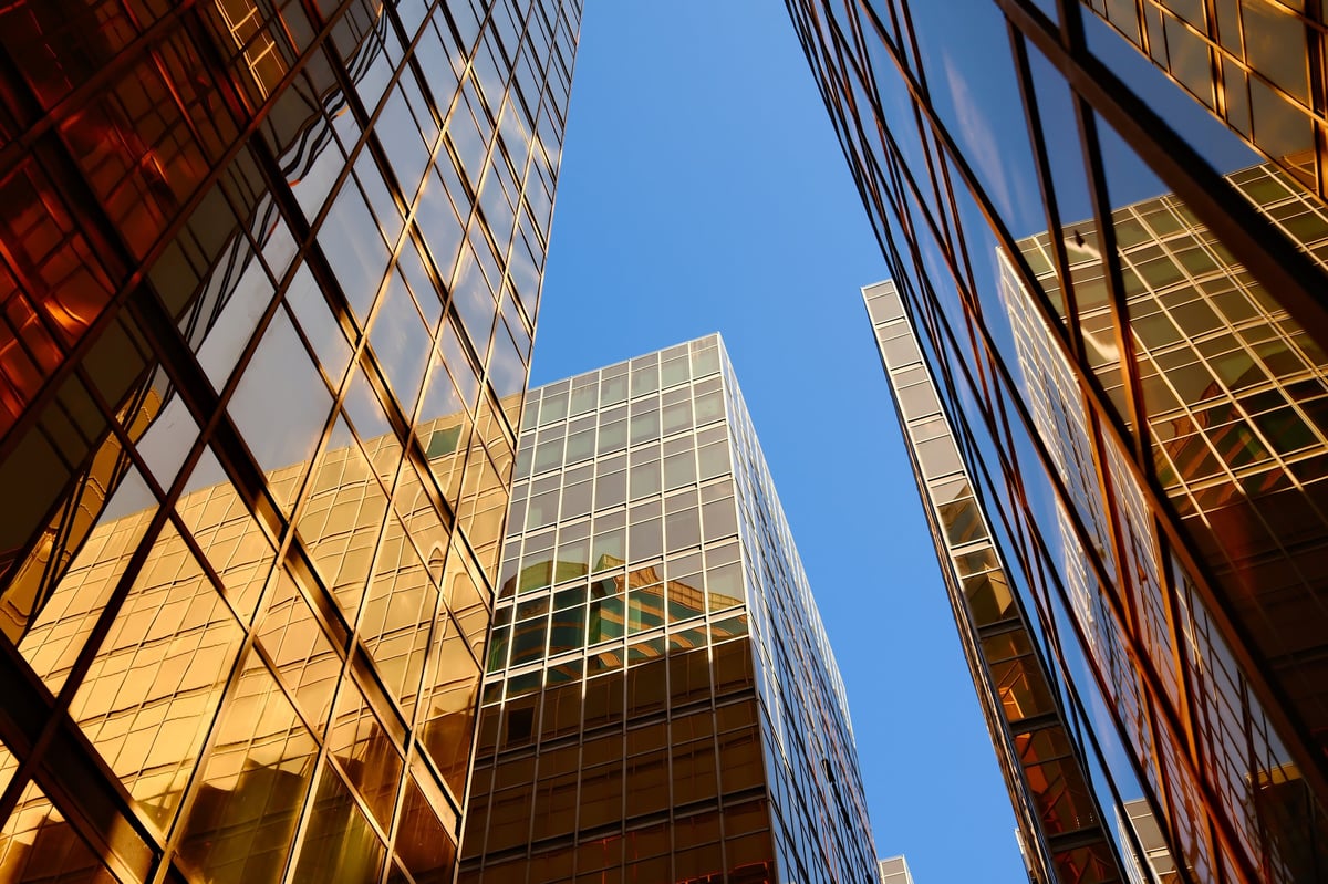 Golden glass skyscrapers converging against clear blue sky in financial district